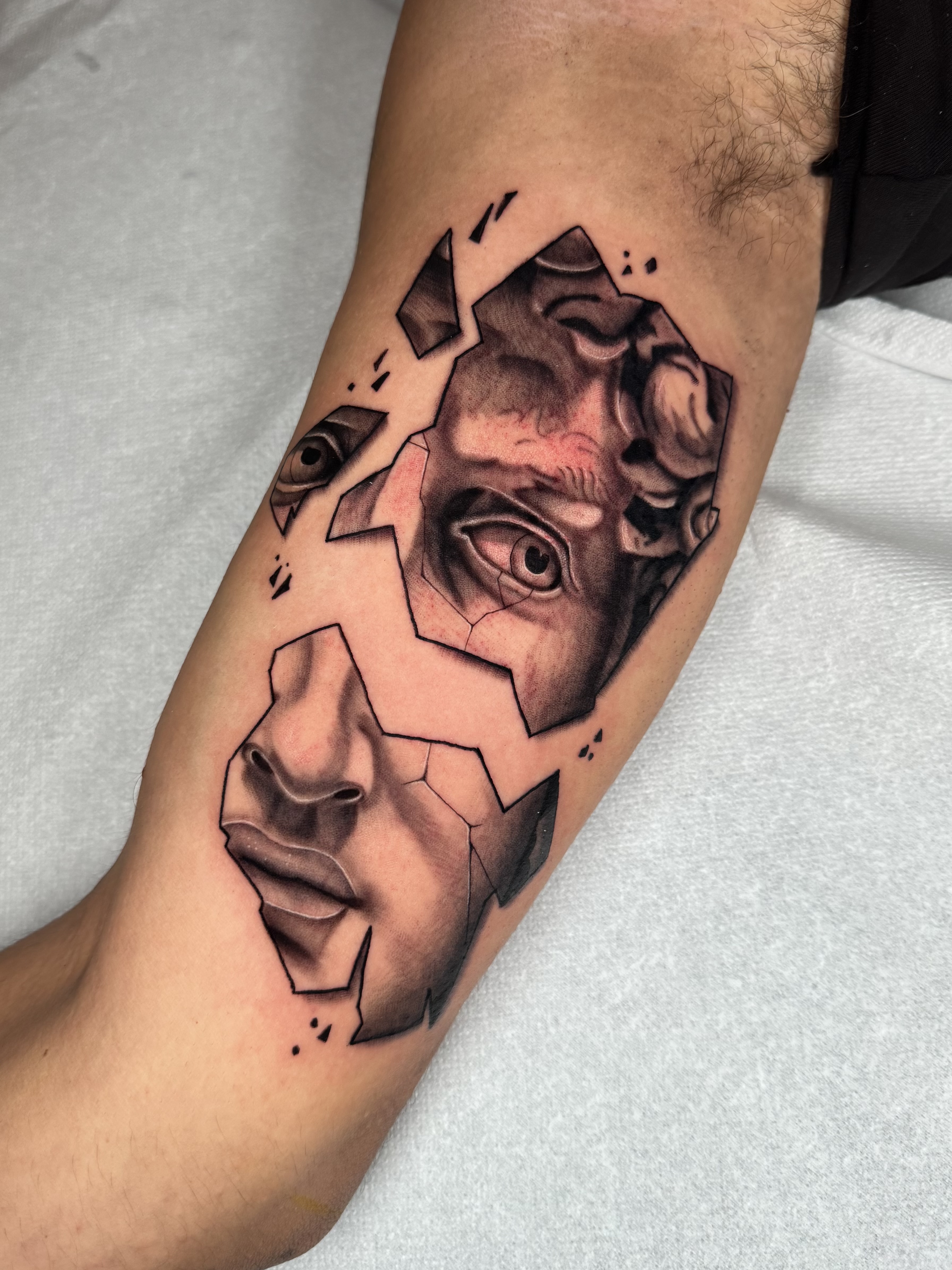 Tatuaggio realistico black and gray con volti geometrici realizzato da Andrea N. Agnelli