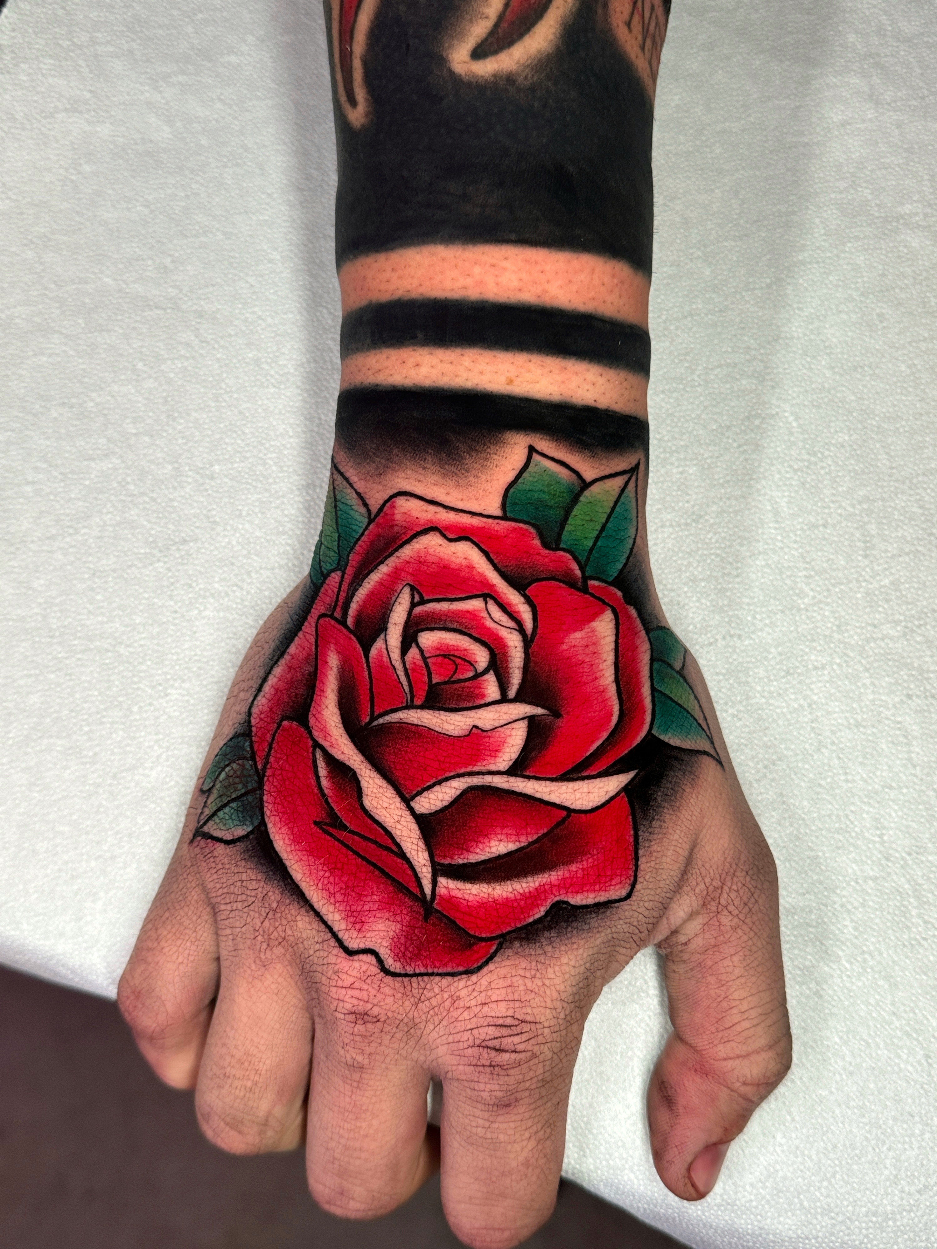 Tatuaggio neo traditional rosa sulla mano realizzato da Thomas Morello AKA SAZE