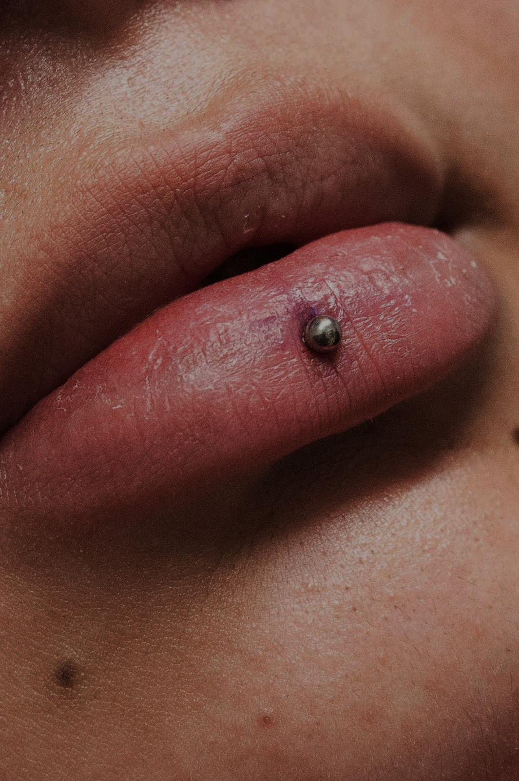 Piercing al labbro con gioiello sferico realizzato da Xhenis Gega