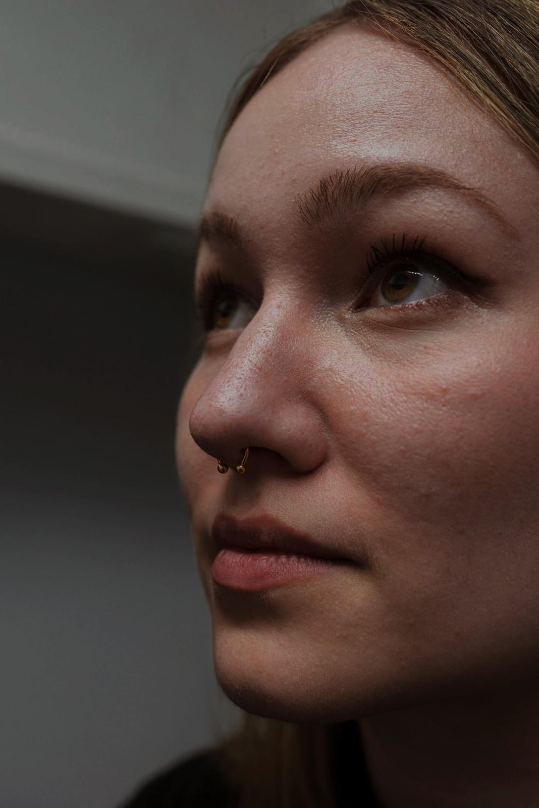 Piercing al setto con gioiello dorato realizzato da Xhenis Gega