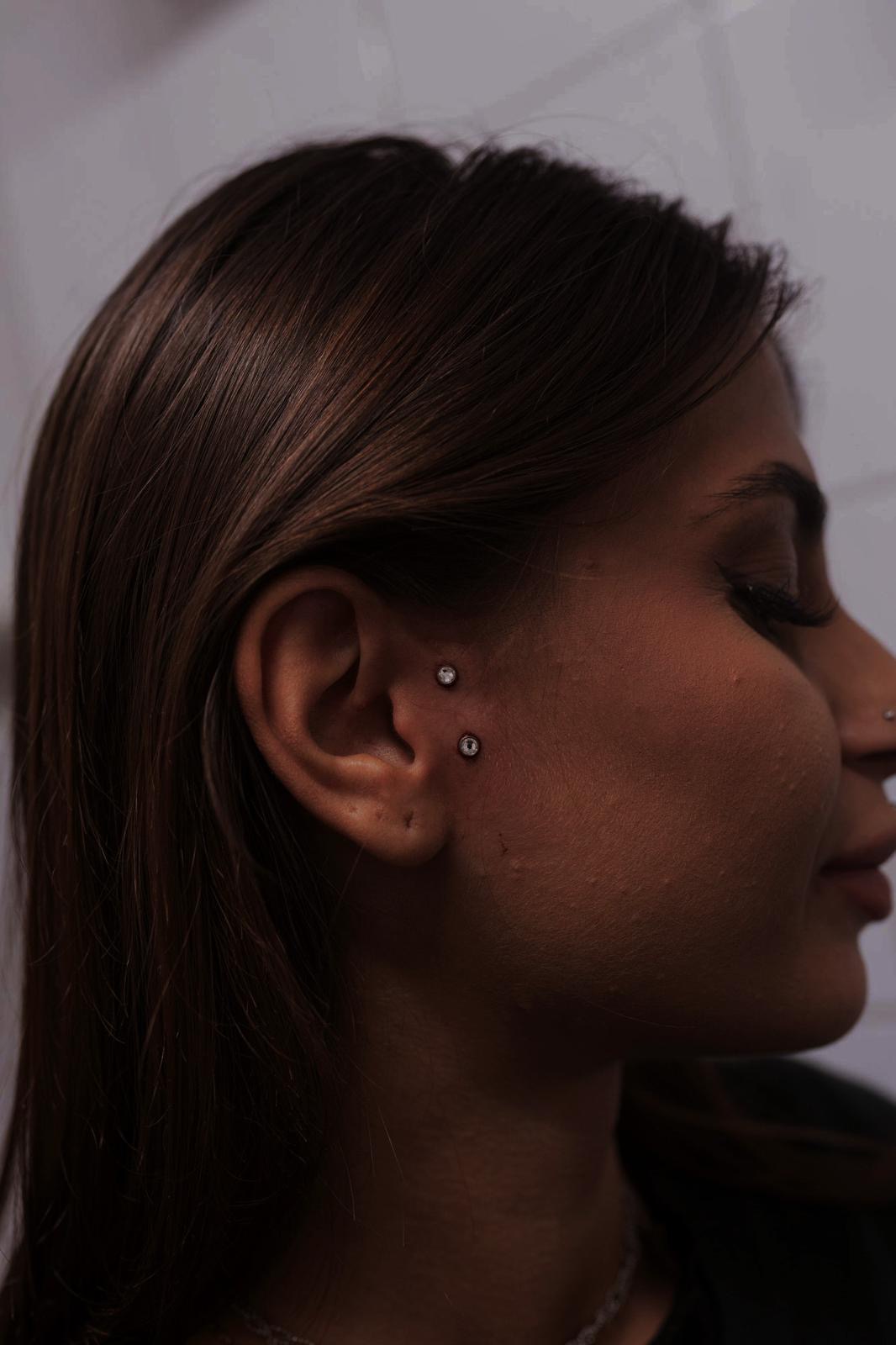 Due piercing sul viso con punti luce realizzati da Xhenis Gega